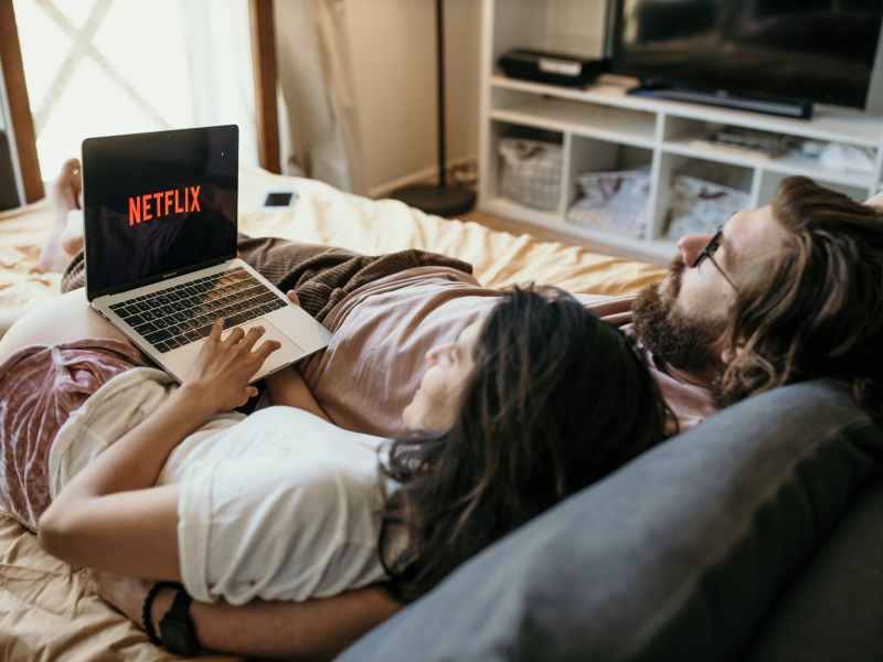 man and woman lying on bed using laptop computer