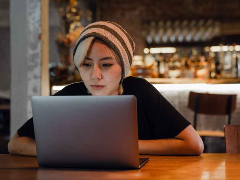 young woman watching movie on laptop in cafe
